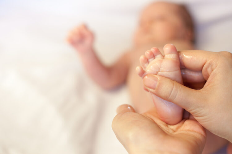 Der Fuß eines Babys wird bei eine Babymassage mit Öl verwöhnt.